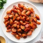 A plate of bite sized roasted carrots with fresh herbs sprinkled on top.