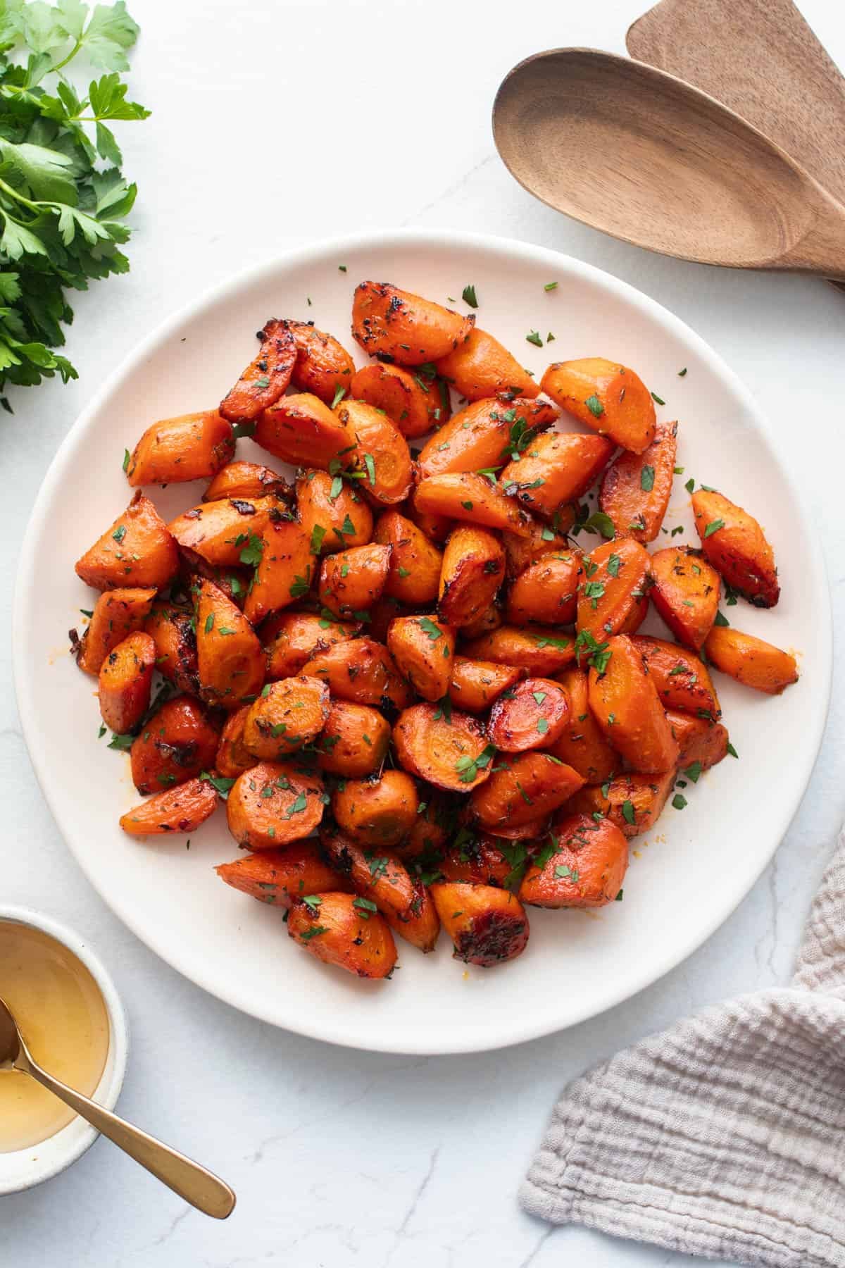 A plate of bite sized roasted carrots with fresh herbs sprinkled on top.