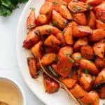 A plate of bite sized roasted carrots with a spoon.