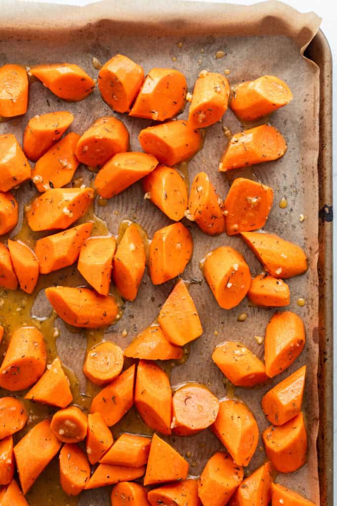 Bite sized carrots spread out on a baking sheet.