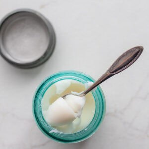 a blue glass filled with rendered lard with a spoon pulling some out of the jar.