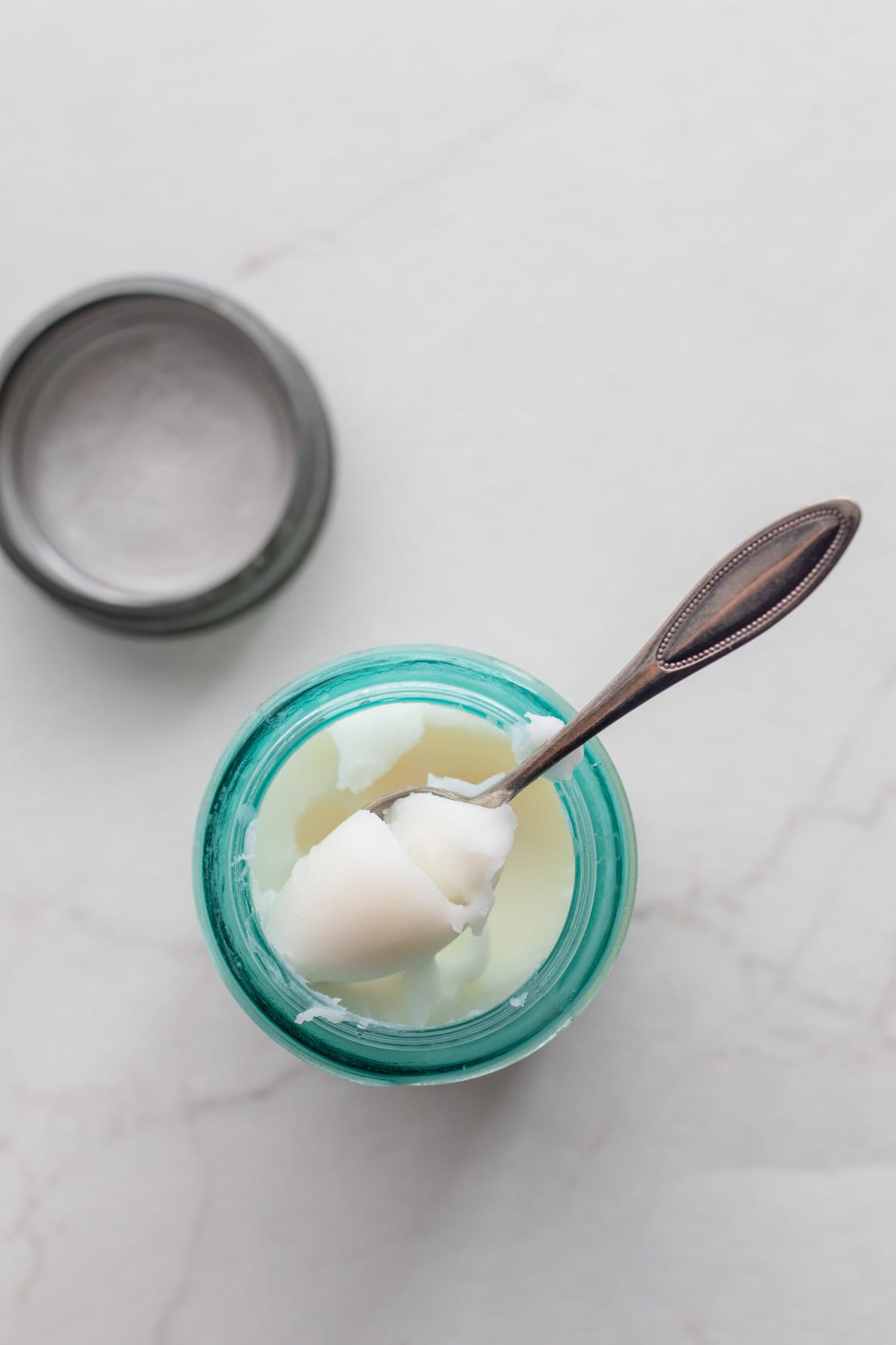 a blue glass filled with rendered lard with a spoon pulling some out of the jar.