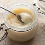 A jar of tallow with a spoon scooping some out.