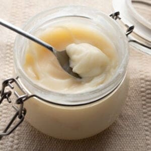 A jar of tallow with a spoon scooping some out.