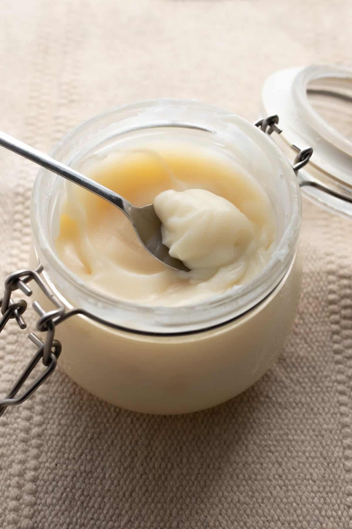 A jar of tallow with a spoon scooping some out.