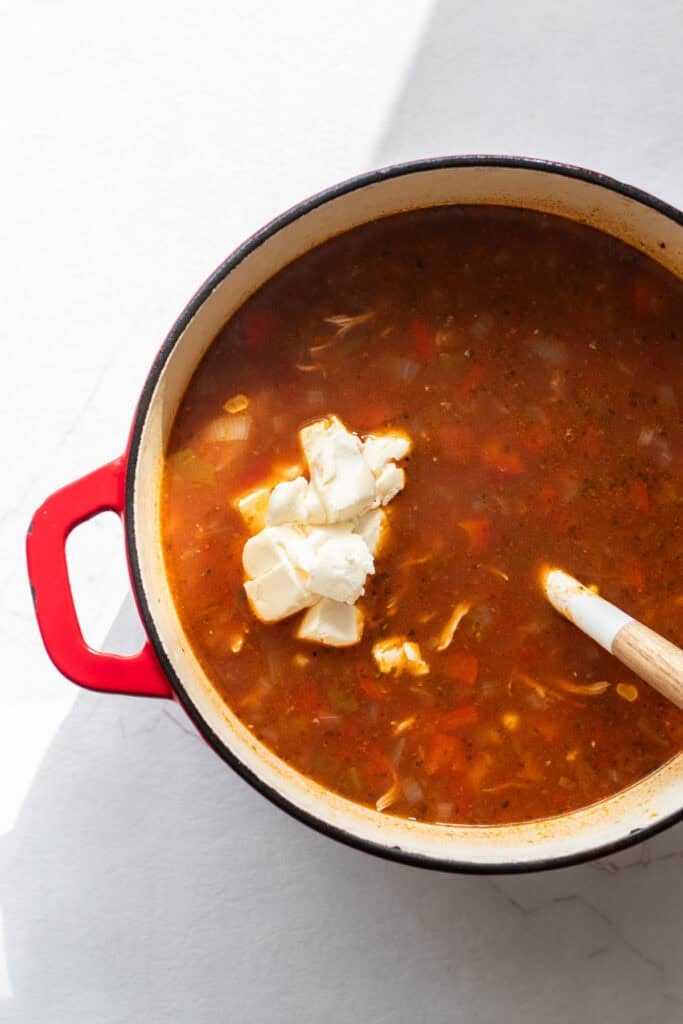 softened cream cheese block added to a large dutch oven full of southwest chicken soup.