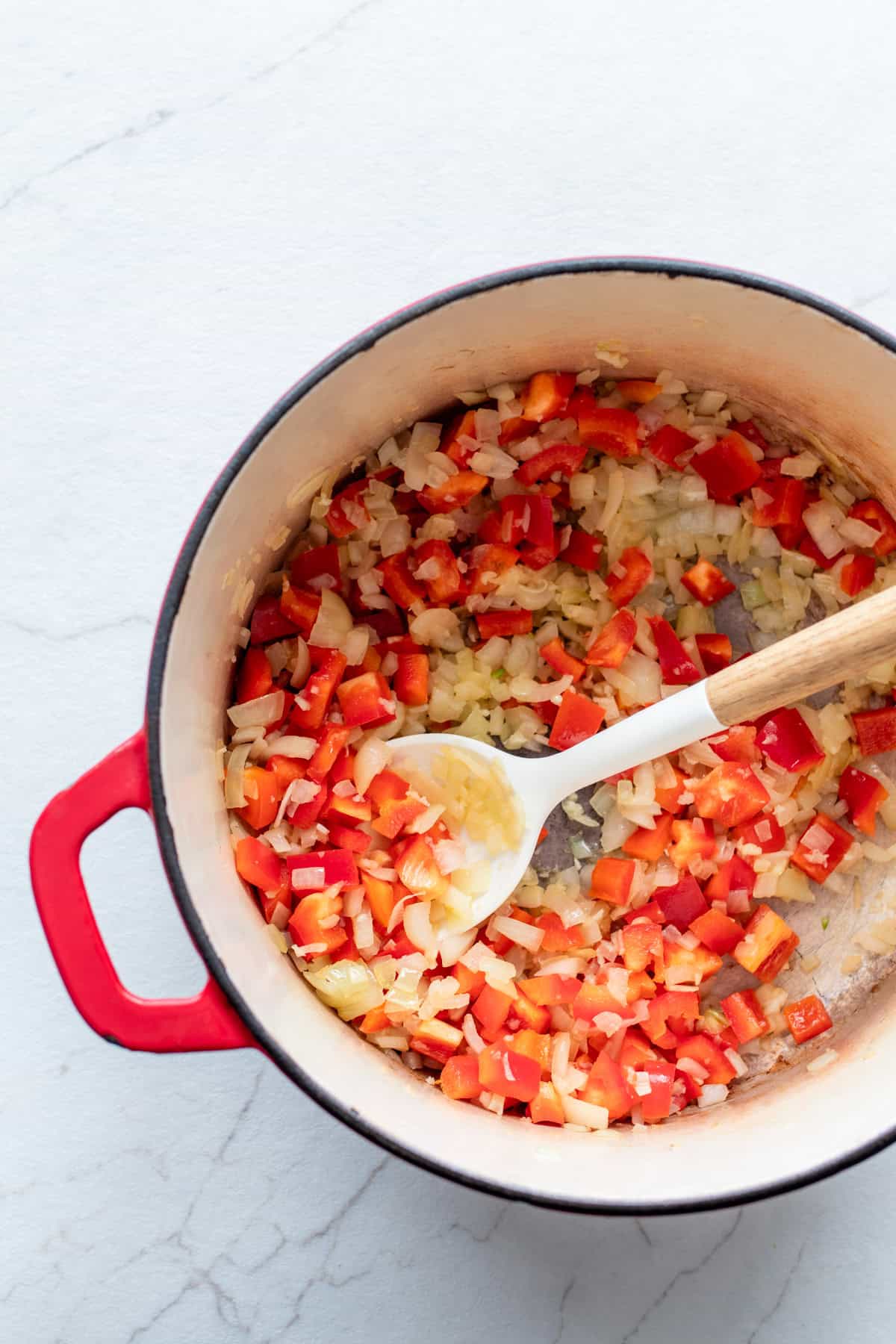 onion and red bell pepper sautéing in a large dutch oven.