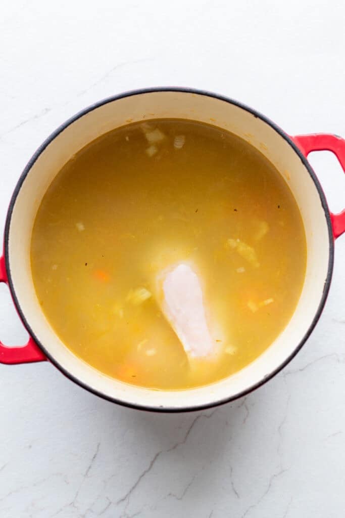 chicken broth and chicken breast added to a large dutch oven with onion and bell peppers.