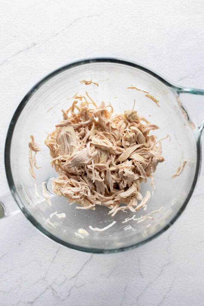 shredded chicken in a large glass measuring bowl.