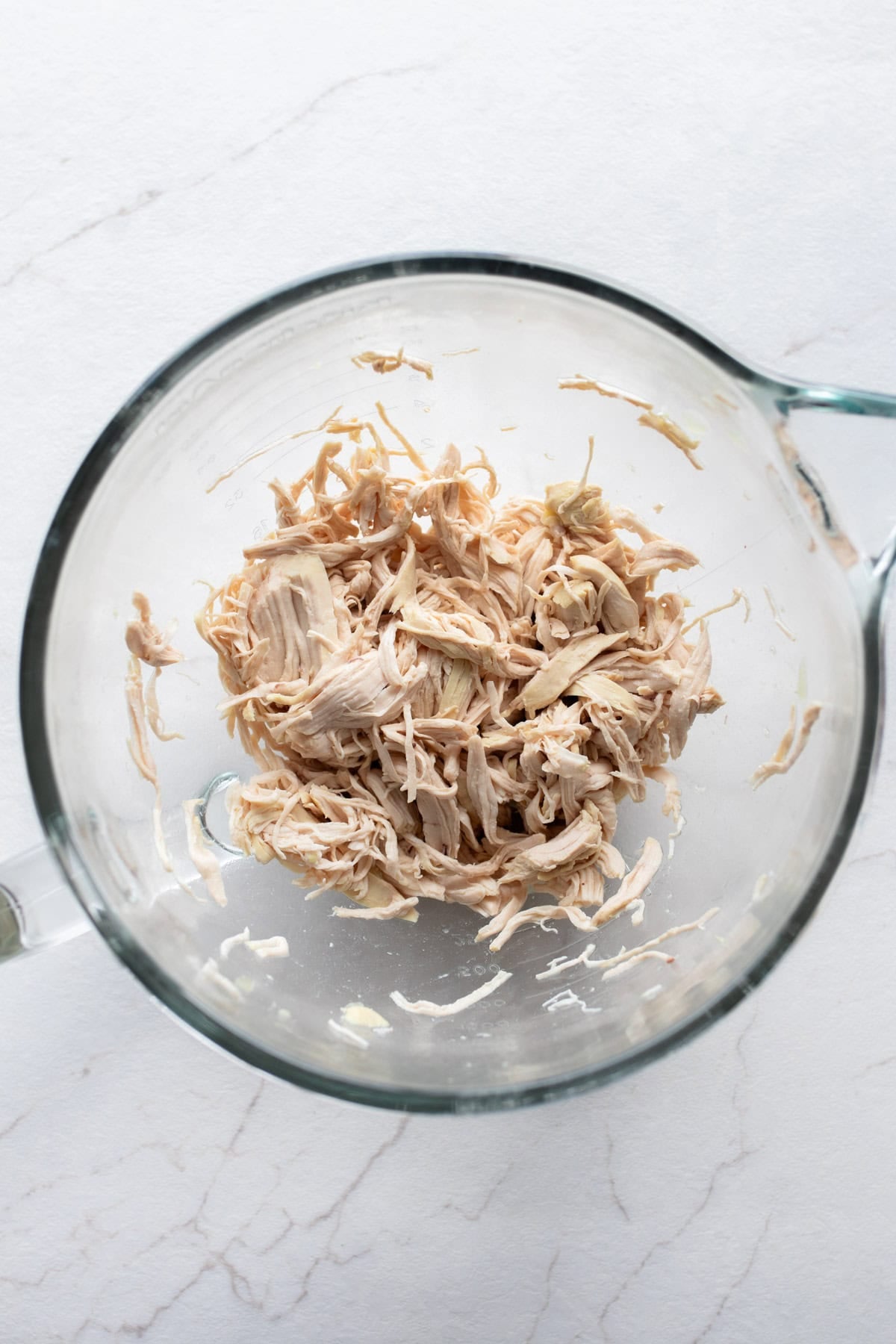 shredded chicken in a large glass measuring bowl.