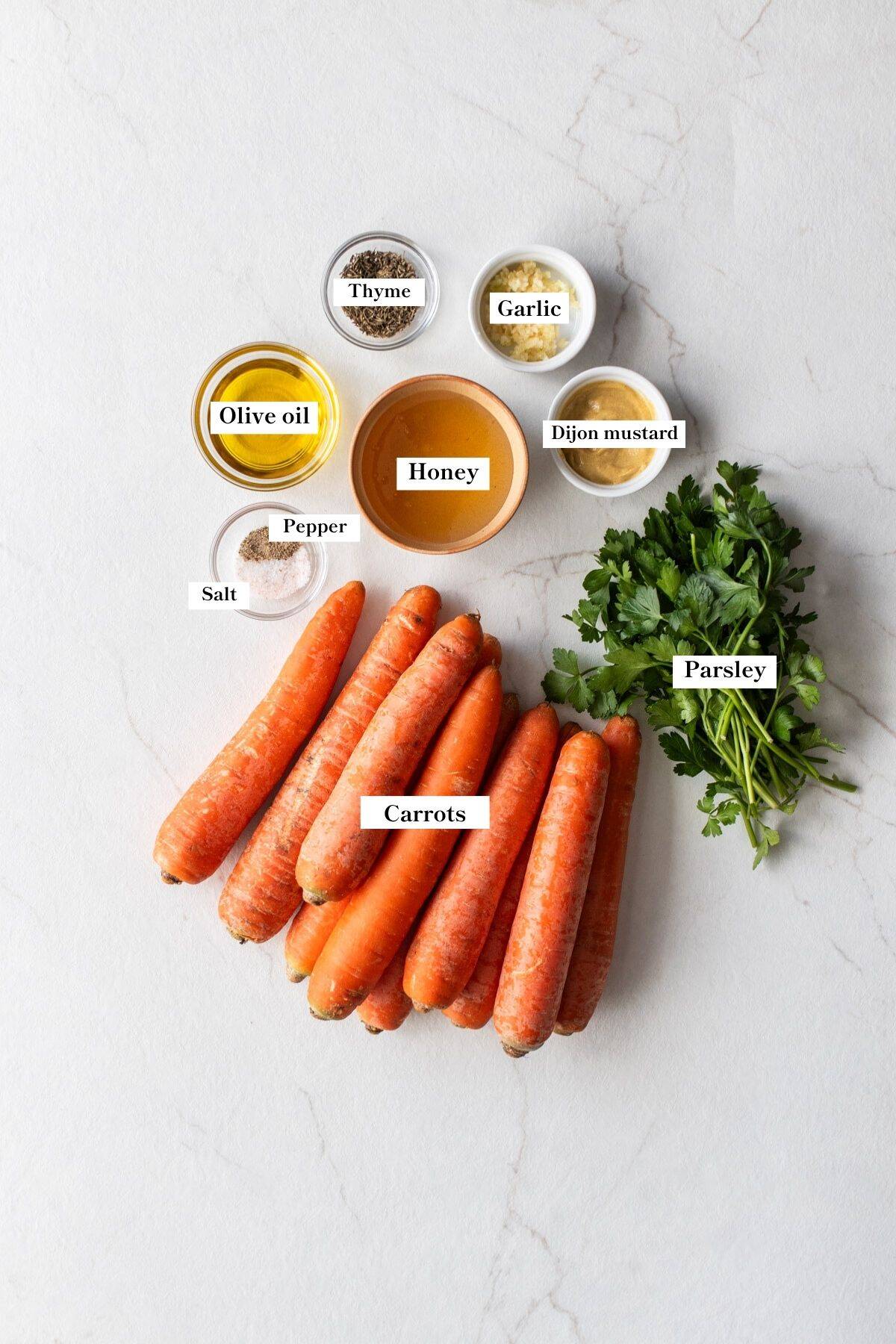 Carrots, fresh herbs, and other ingredients in small bowls on the counter top.