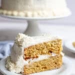 one slice of whole wheat cake with a vanilla buttercream frosting on a white dessert plate.