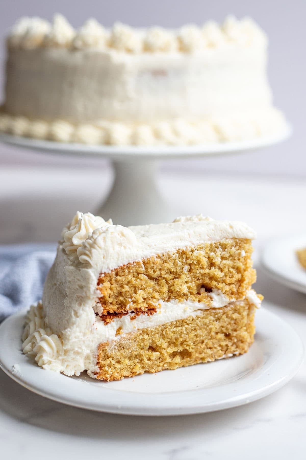 one slice of whole wheat cake with a vanilla buttercream frosting on a white dessert plate.