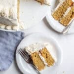 two slices of whole wheat cake on white dessert plates on a marble counter.