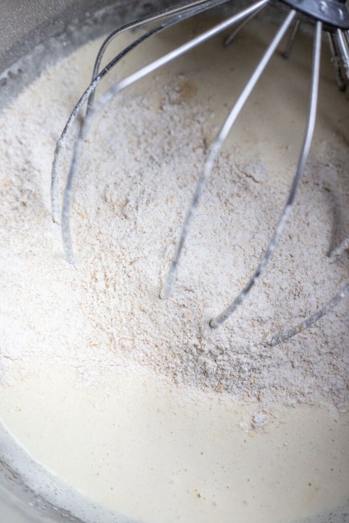 combining dry cake ingredients with wet ingredients in the bowl of a stand mixer.