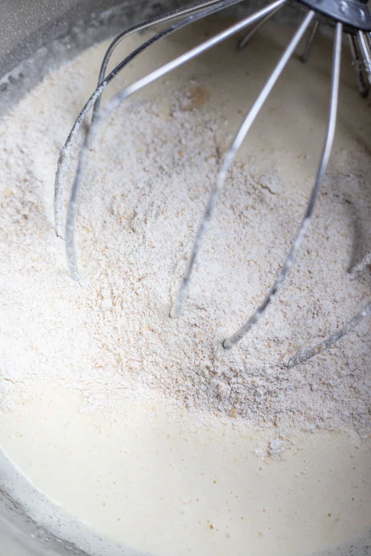 combining dry cake ingredients with wet ingredients in the bowl of a stand mixer.