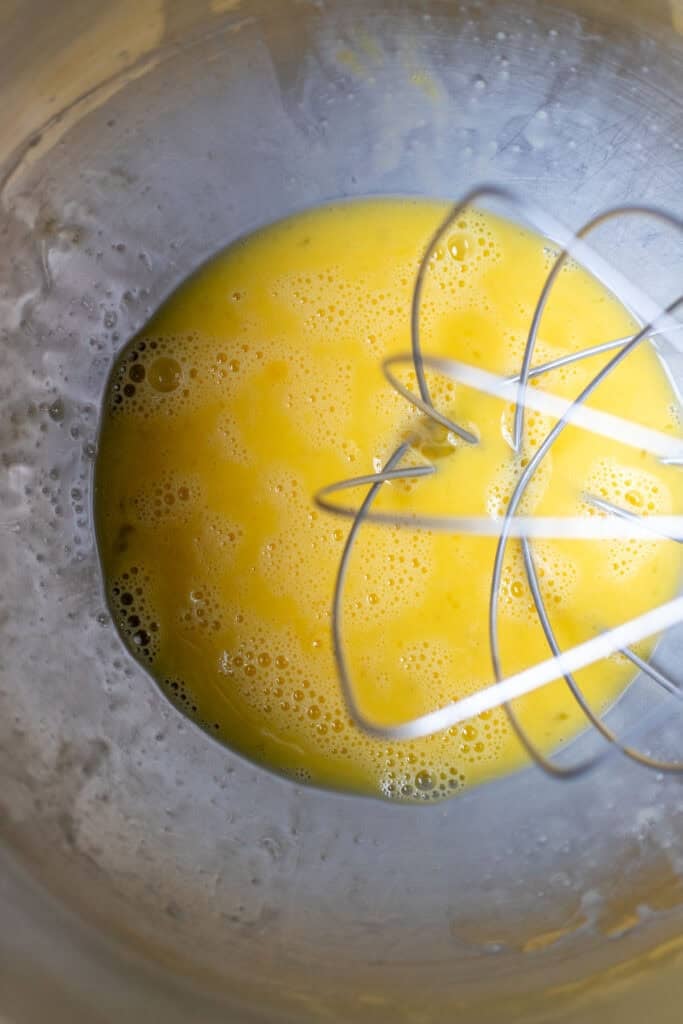 four eggs in the metal bowl of a stand mixer.