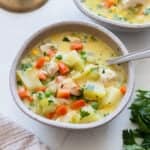 A bowl on a countertop filled with chicken pot pie soup with a spoon in it.