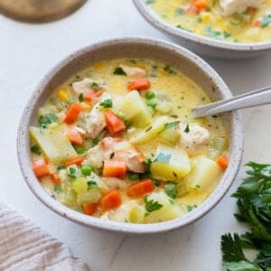 A bowl on a countertop filled with chicken pot pie soup with a spoon in it.