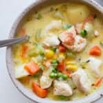 A bowl of chicken pot pie soup with a spoon in it.