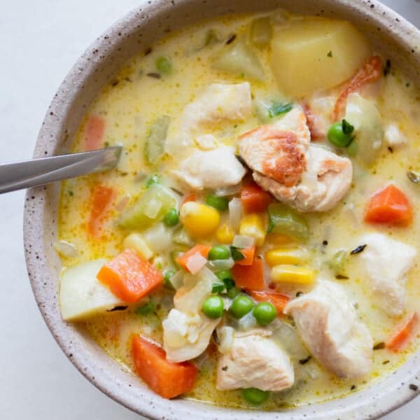 A bowl of chicken pot pie soup with a spoon in it.