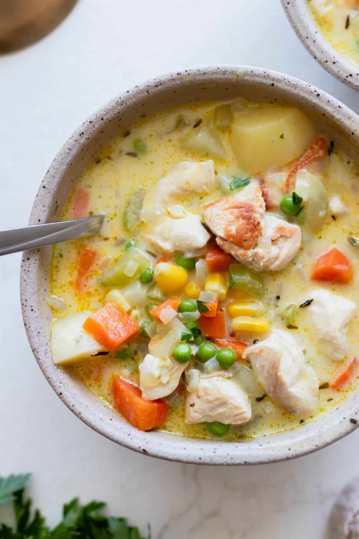 A bowl of chicken pot pie soup with a spoon in it.