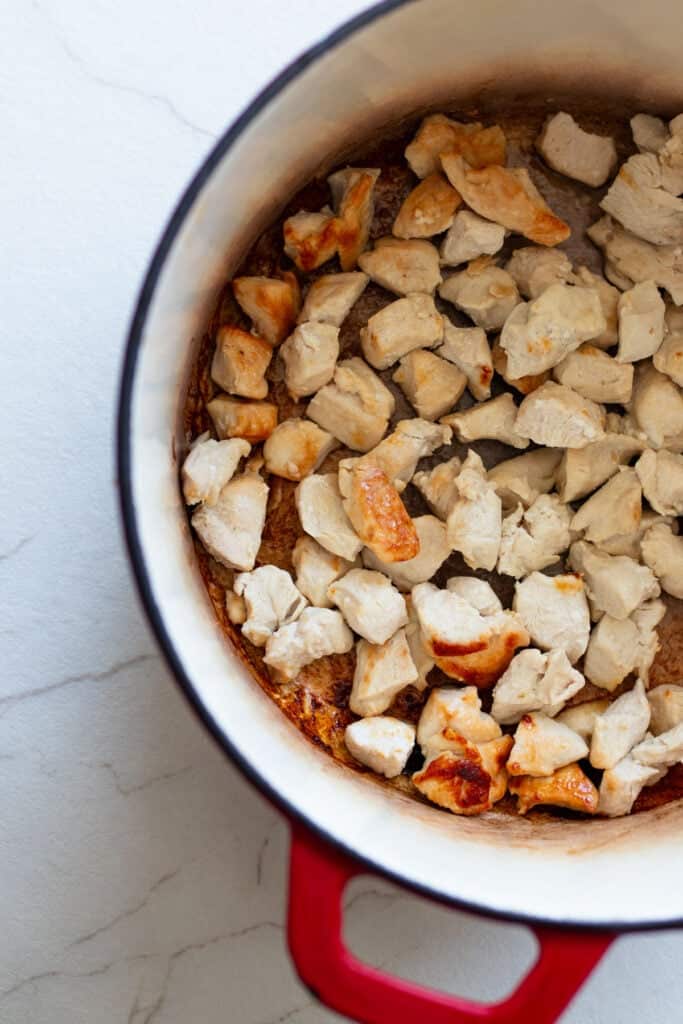 Cooked chicken pieces in a Dutch oven.