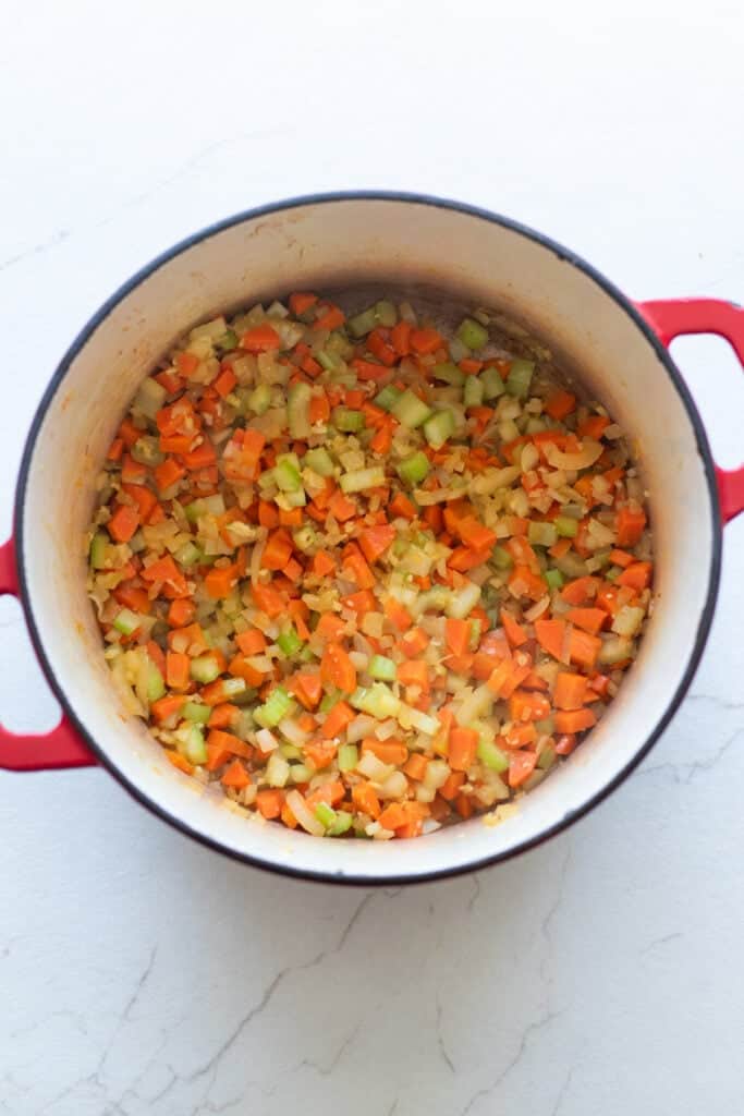 Diced carrots and celery in the bottom of a Dutch oven.