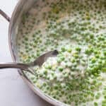 Cream peas in a sauce pan with a spoon scooping up some.