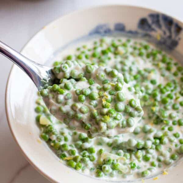 A bowl full of cream peas with a spoon in it.