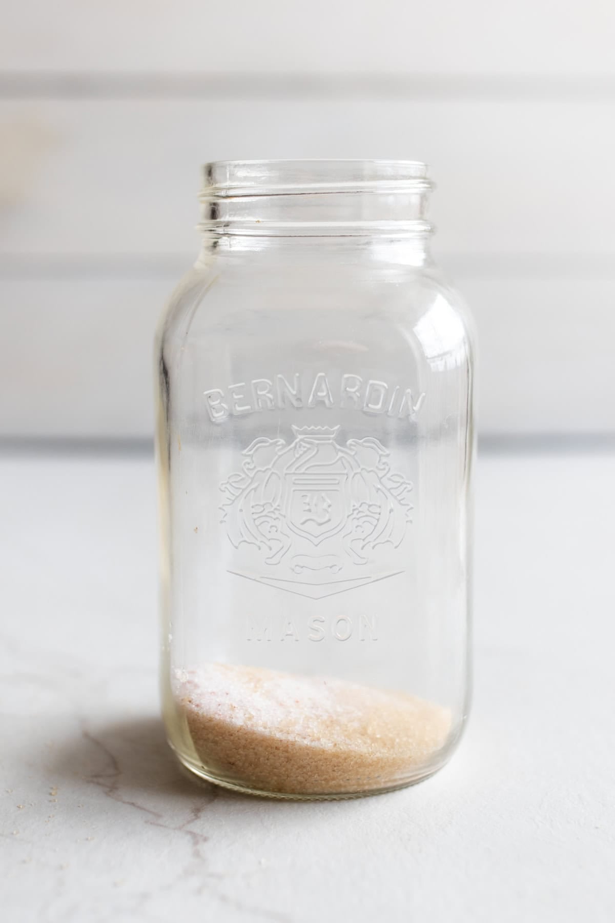 A large mason jar with sugar and salt on the bottom.