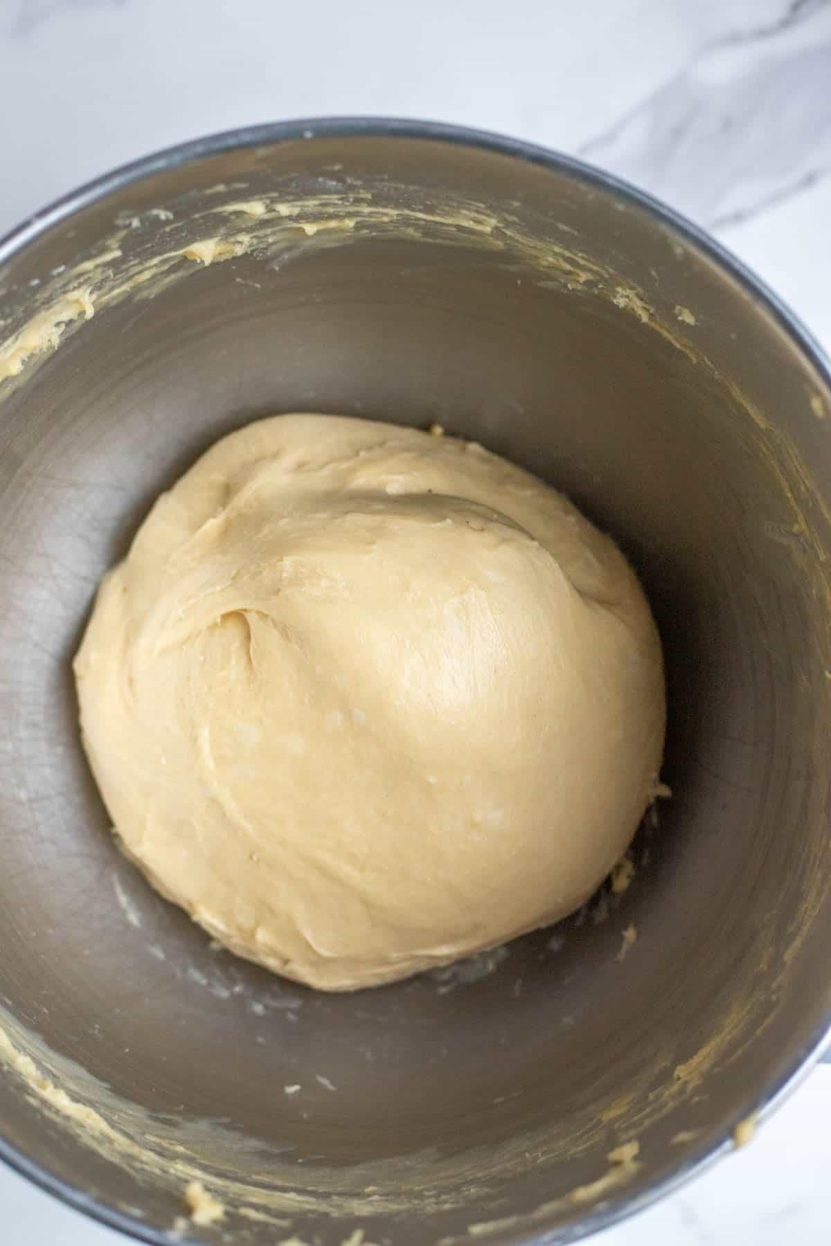 Freshly kneaded sourdough in a stainless steel mixing bowl.