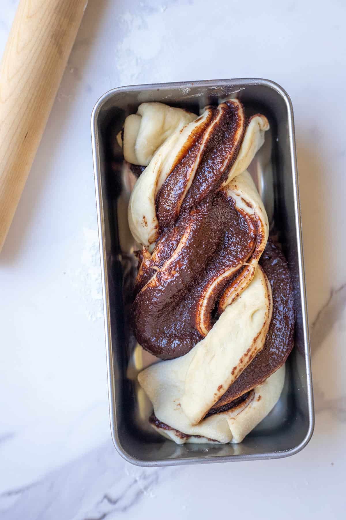Sourdough babka inside of a stainless steel loaf pan.