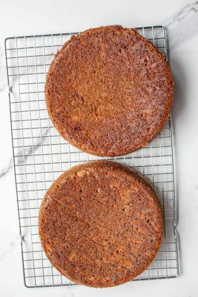 two round cakes on a metal rack to cool.
