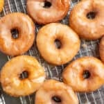 nine glazed sourdough donuts on a metal wire cooling wrack.
