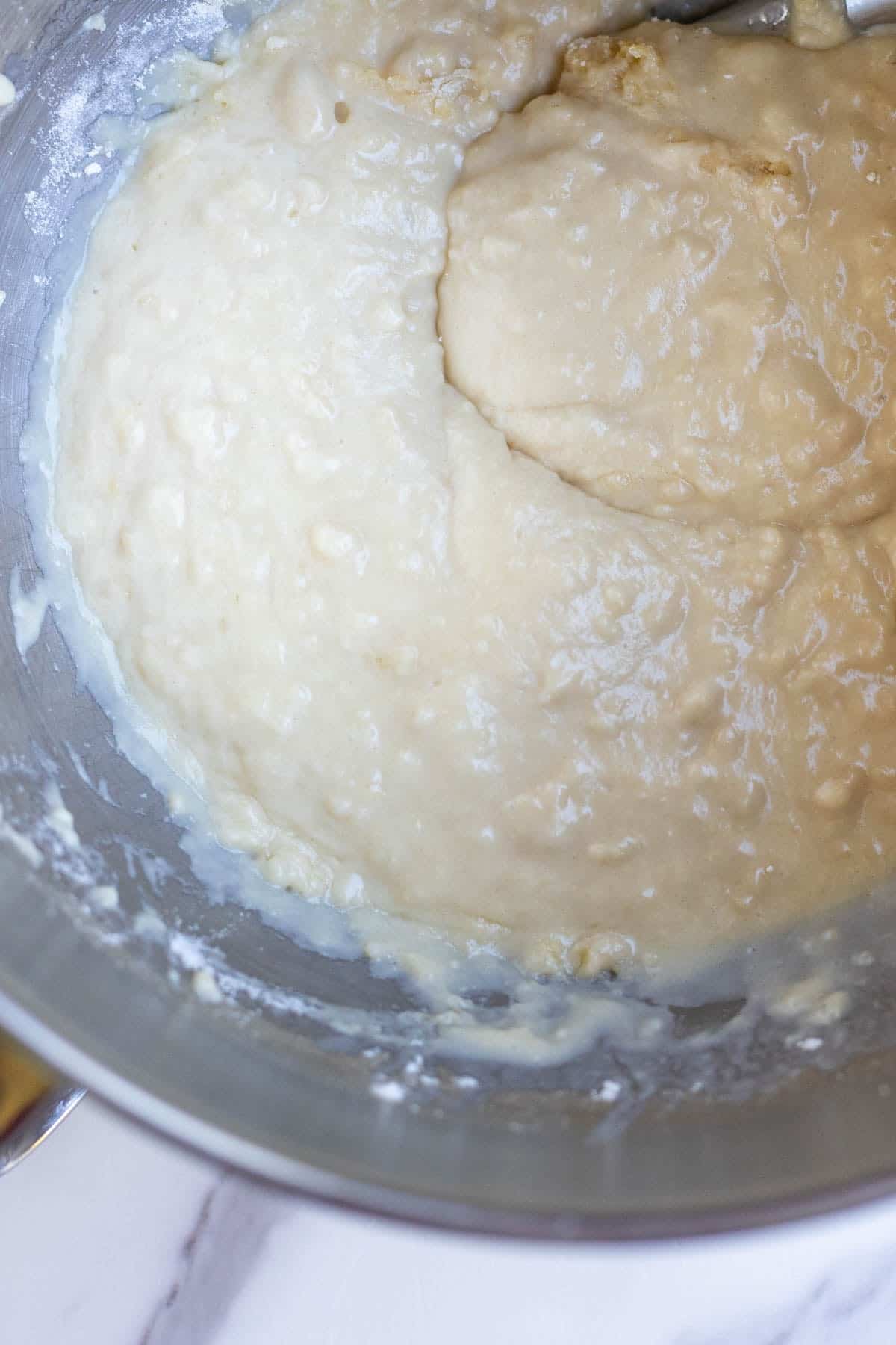 Butter mixture and flour added to stainless steel mixing bowl.