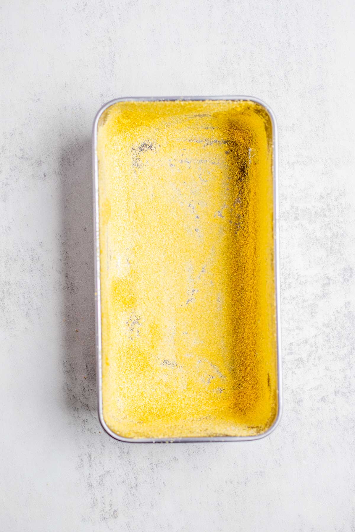 A loaf pan dusted with cornmeal.