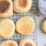 browned english muffins cooling on a wire rack on the kitchen counter.
