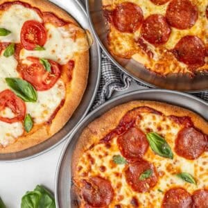Three different pizzas next to each other on a counter top.