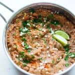 A sauce pan of homemade refried beans with garnishing on top.