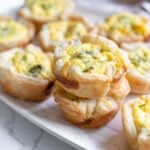 Mini quiches stacked on a plate.