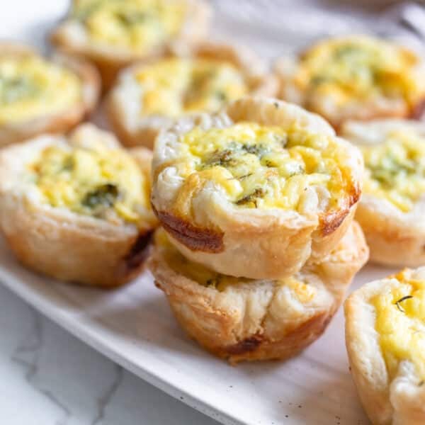 Mini quiches stacked on a plate.