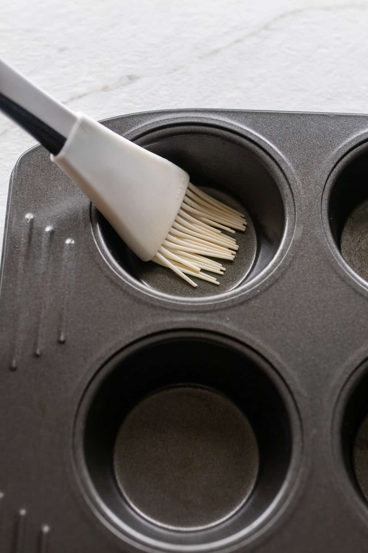 A silicone brush in a muffin tin.