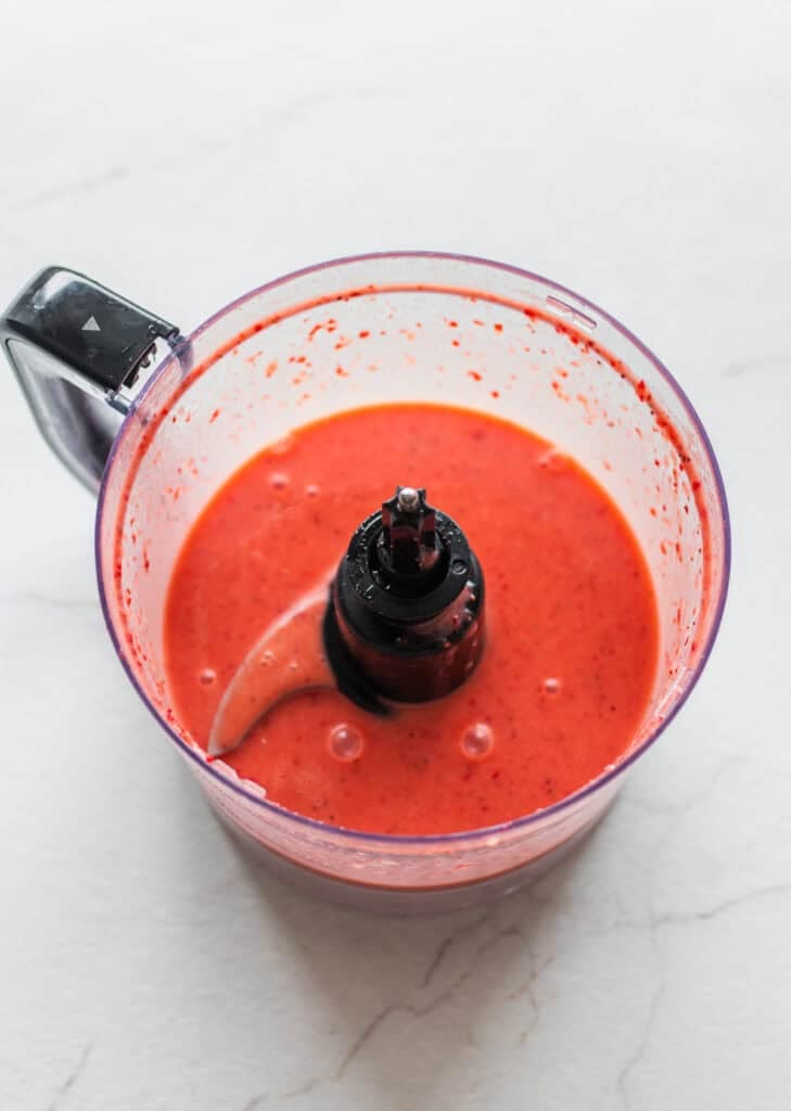 Strawberries and other ingredients mixed together in a food processor.