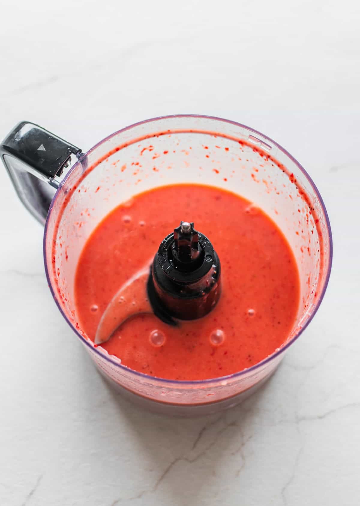 Strawberries and other ingredients mixed together in a food processor.