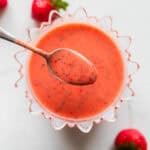 A bowl of strawberry salad dressing with a spoon scooping some out.