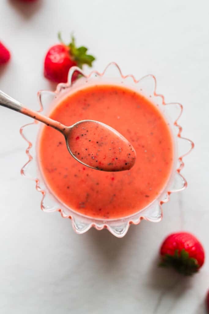 A bowl of strawberry salad dressing with a spoon.