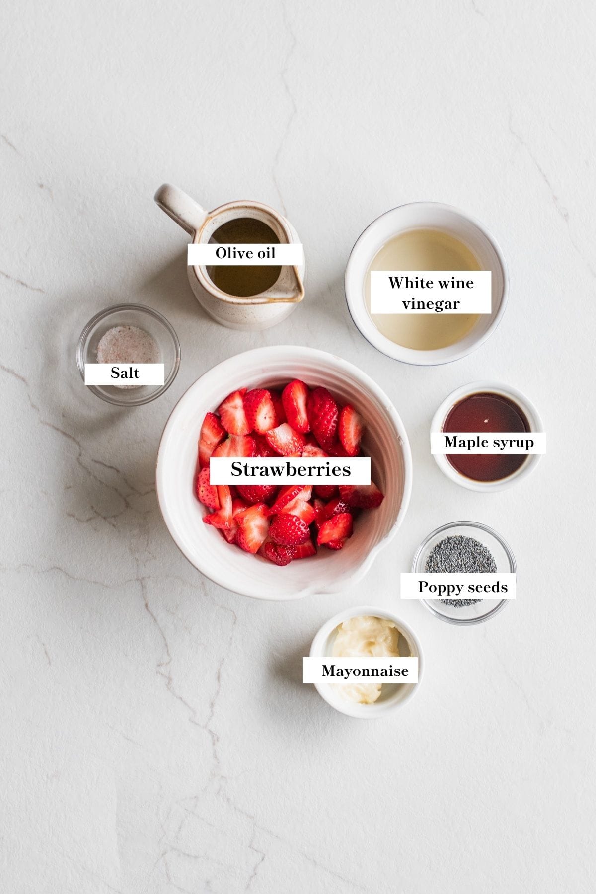 Ingredients for strawberry salad dressing in bowls on a counter top.