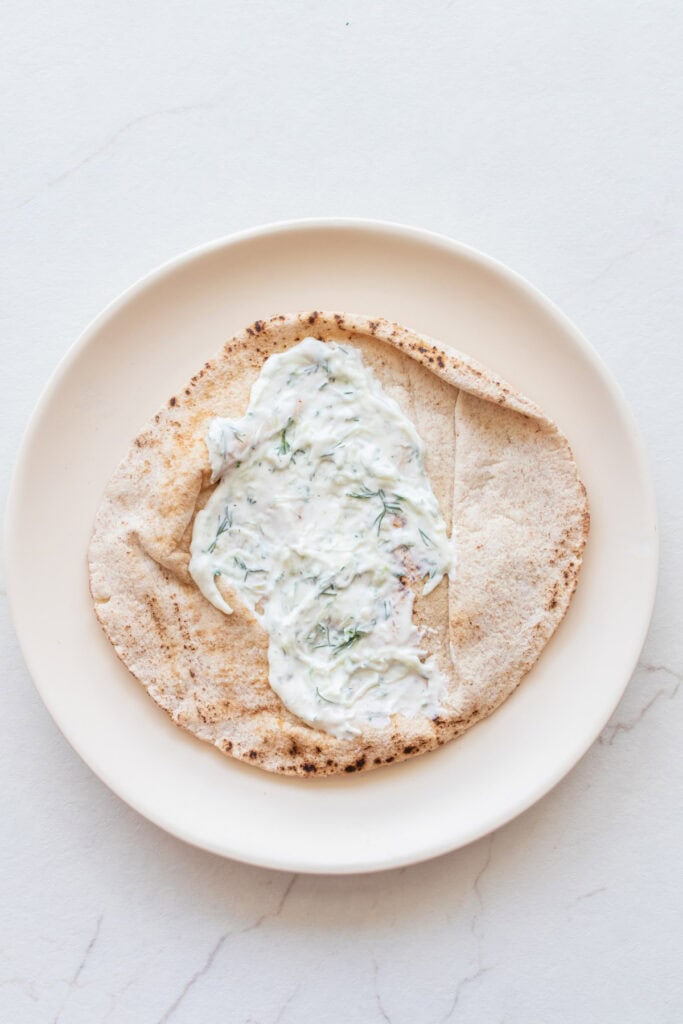 Tzatziki sauce on a pita on a plate.