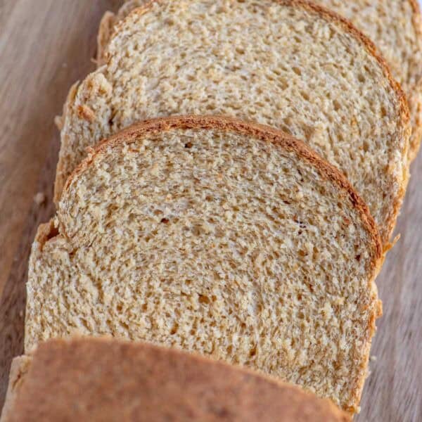 Three slices of freshly milled sandwich bread cut from a loaf on a cutting board.